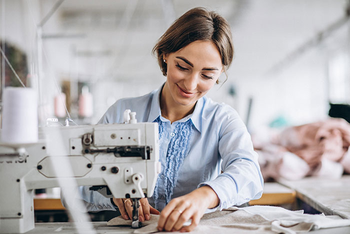 Woman sewing fabric using a sewing machine, making an elaborate wedding dress design