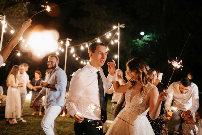 A perfect bachelorette with family drama: a happy bride and groom dance with sparklers at an outdoor night party. A perfect bachelorette with family drama: a happy bride and groom dance with sparklers at an outdoor night party.
