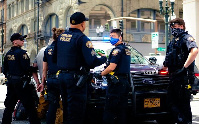 Police officers detaining a person next to police car in city unsettling thing found about friend