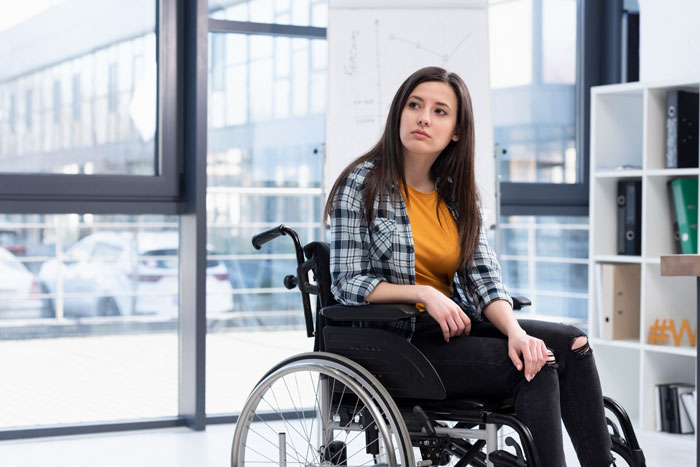 Young woman in wheelchair indoors reflecting on situation involving ableist boyfriend Young woman in wheelchair indoors reflecting on situation involving ableist boyfriend
