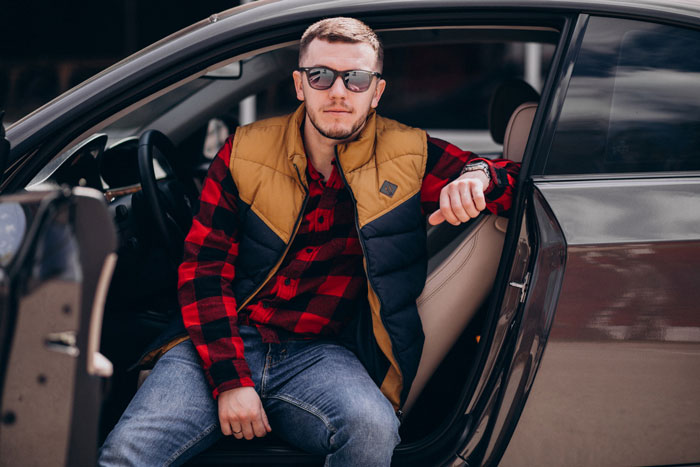 Man sitting in car door showing confident attitude after breakup Man sitting in car door showing confident attitude after breakup