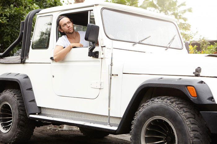 Man sitting in a white off-road vehicle looking contemplative Man sitting in a white off-road vehicle looking contemplative
