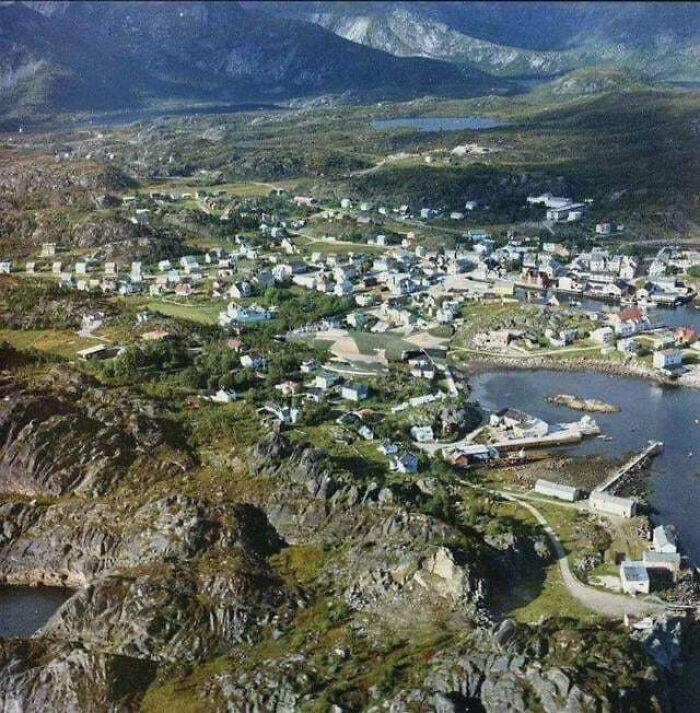 Aerial view of a coastal village surrounded by rocky hills and water
