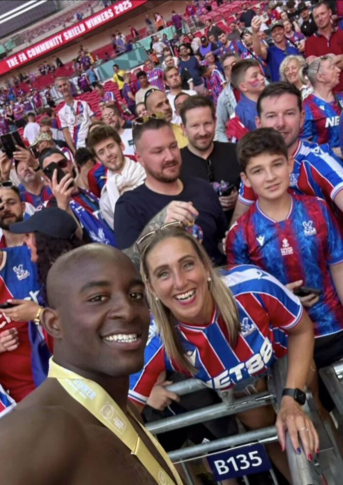 Group selfie at stadium with fans wearing crystal palace jerseys and fa community shield winners banner