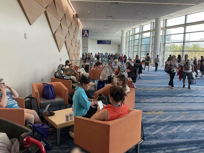 People sitting and standing in spacious convention center lounge area