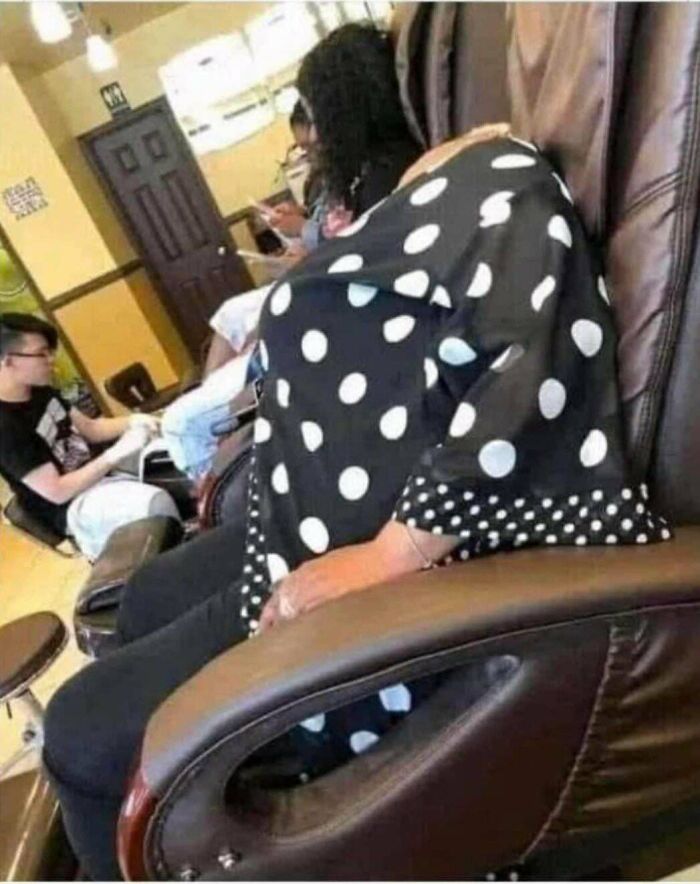 Polka dot blanket covers seated person in nail salon with people in background