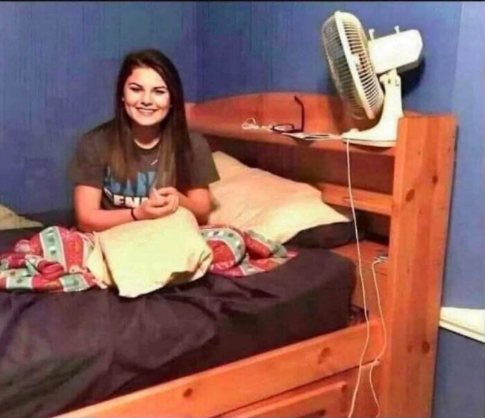 Woman sitting on bed in room with tall fan on wooden headboard hidden cables