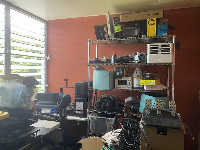 Cluttered shelving unit with electronic equipment in a room with natural light