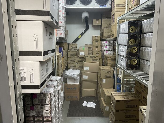 Storage room filled with stacked boxes and frozen ceiling pipe