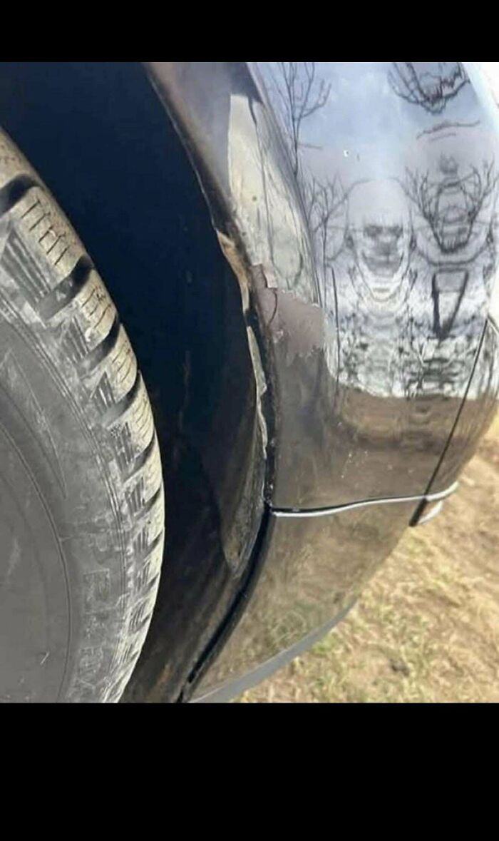 Reflection of a distorted skull face on car surface near tire in hidden details photo