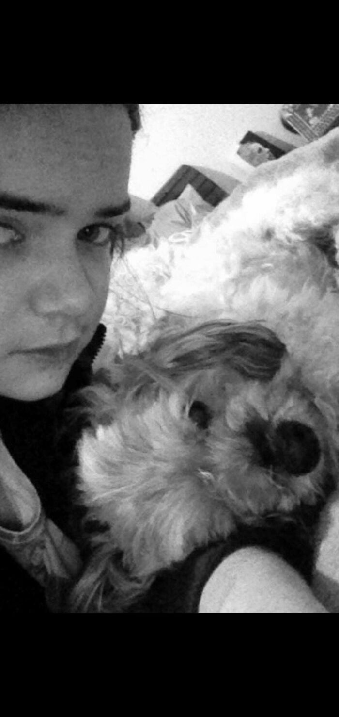 Black and white close-up of person holding fluffy dog indoors