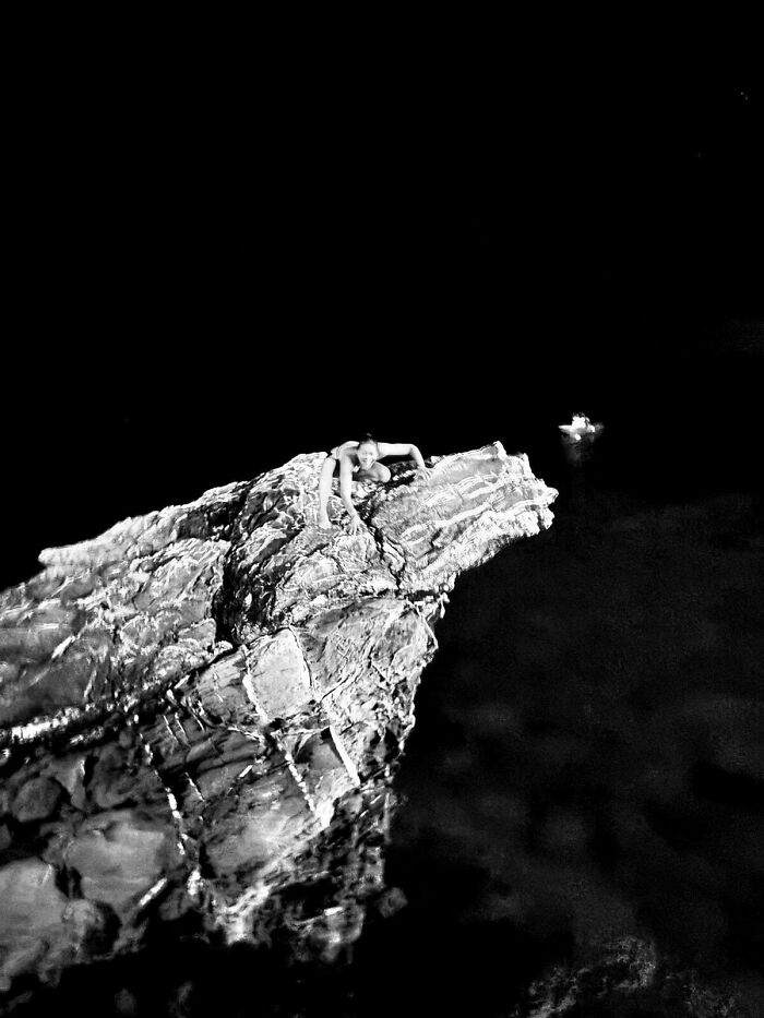 Black and white image of person climbing rock at night with hidden details