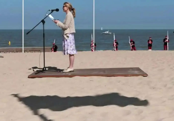 A woman on a beach standing on a floating platform, an optical illusion making it a when you see it picture.