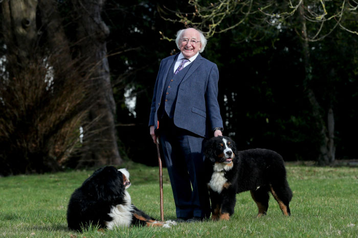 Wholesome world leader smiling outdoors with two dogs on a grassy field