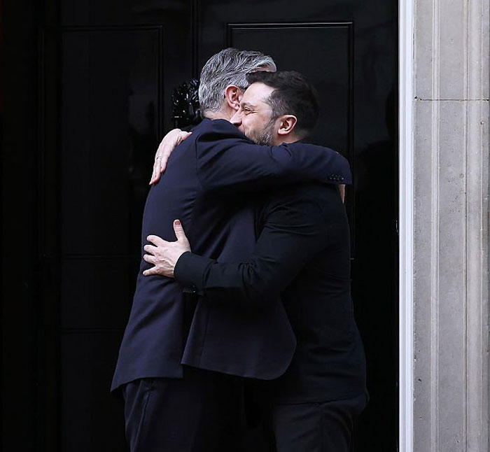 Two world leaders embracing warmly outside a black door