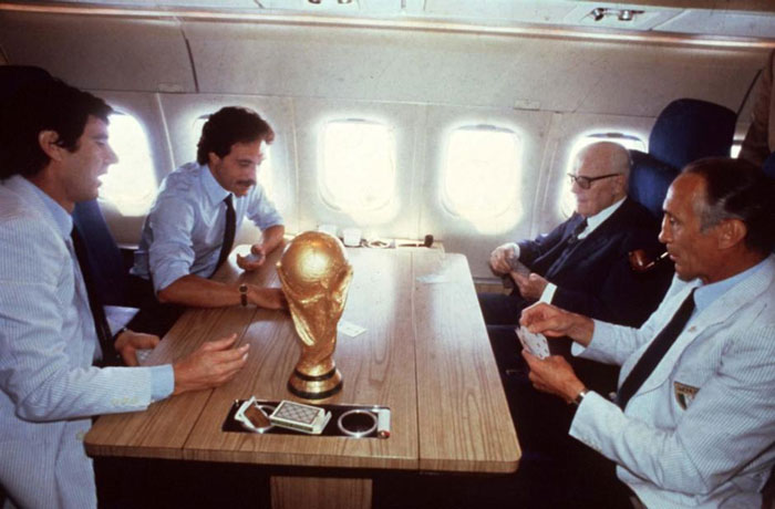 World leaders playing cards on plane with World Cup trophy on table