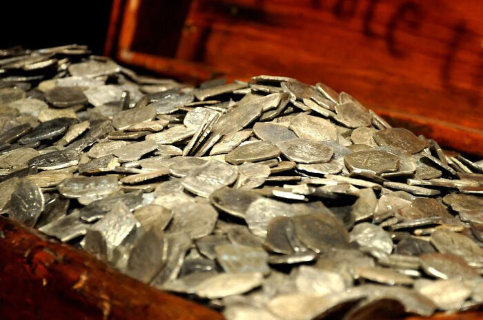 A chest full of lost treasures, specifically silver coins, representing billions in wealth from a history researcher's findings.