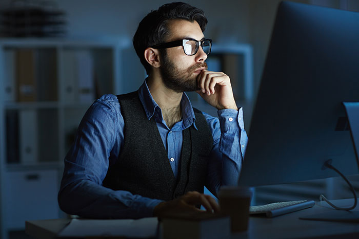 Man working late on computer, reflecting deeply about involvement promises