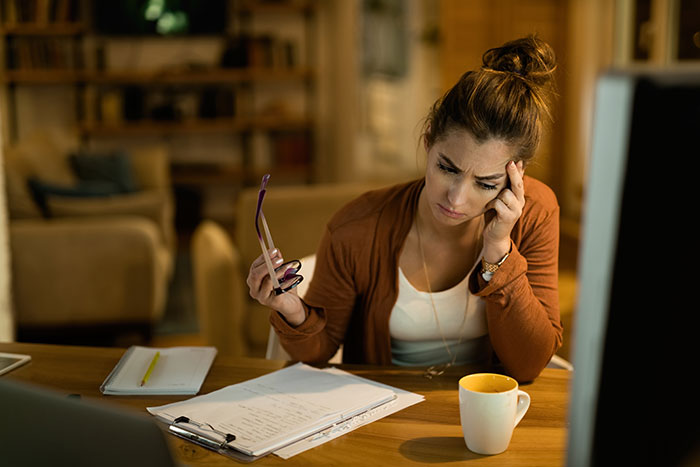 Stressed woman at home desk reflecting on relationship issues