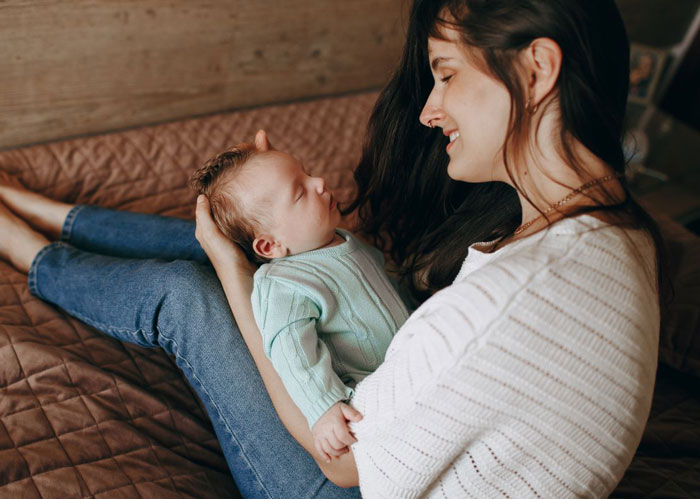 A pregnant woman holding her newborn baby, considering divorce from her husband who is grieving his late ex. A pregnant woman holding her newborn baby, considering divorce from her husband who is grieving his late ex.