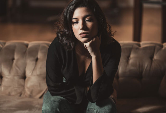 A thoughtful pregnant woman sitting on a couch, contemplating asking her husband for divorce after he starts grieving. A thoughtful pregnant woman sitting on a couch, contemplating asking her husband for divorce after he starts grieving.