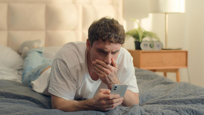 Man shocked looking at phone with numerous Tinder matches Man shocked looking at phone with numerous Tinder matches