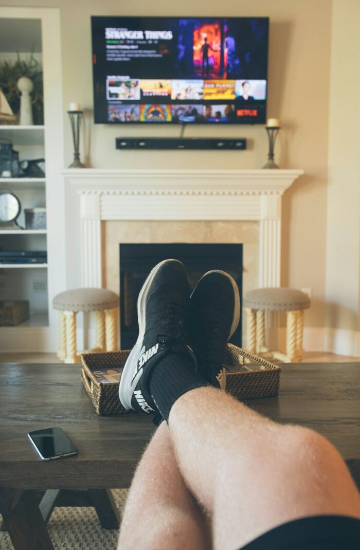 Feet resting on a coffee table in front of a TV, illustrating a moment of solitude for divorced people.