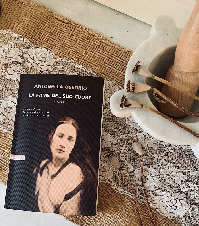 Book titled La Fame Del Suo Cuore by Antonella Ossorio on lace tablecloth Book titled La Fame Del Suo Cuore by Antonella Ossorio on lace tablecloth