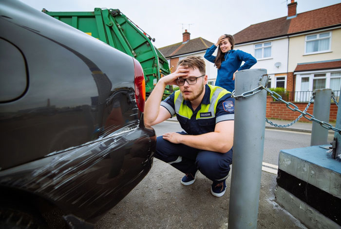 Man inspecting scratch damage on car after crash in residential area Man inspecting scratch damage on car after crash in residential area
