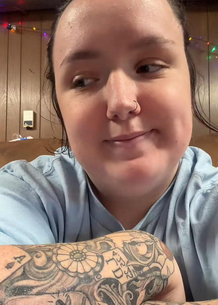 A woman with tattoos on her arm, looking to the side, discussing her best friend who digitally kidnapped her daughter.