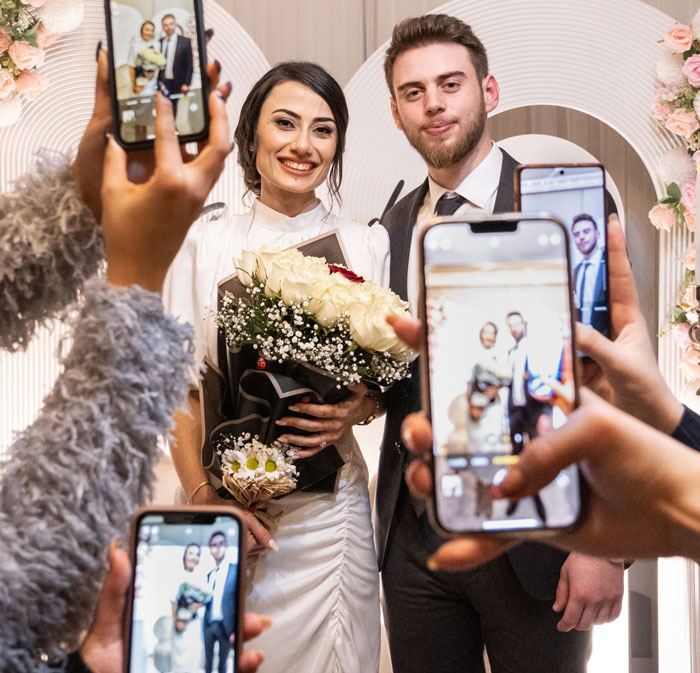 Smiling bride and groom posing for photos, celebrating their wedding day with friends.