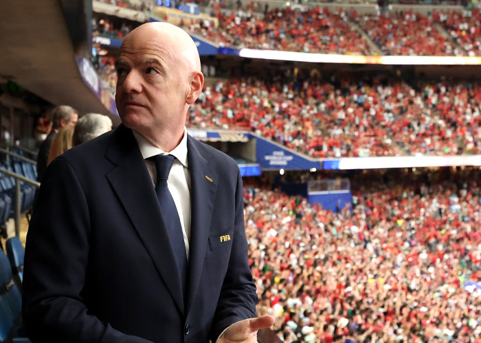 A bald World Cup boss in a suit looking out over a crowded soccer stadium, revealing a scandalous hypocritical act. A bald World Cup boss in a suit looking out over a crowded soccer stadium, revealing a scandalous hypocritical act.