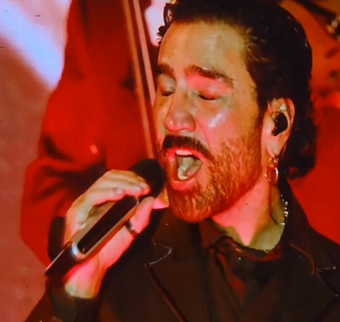 Singer passionately performing on stage with microphone and ear monitors