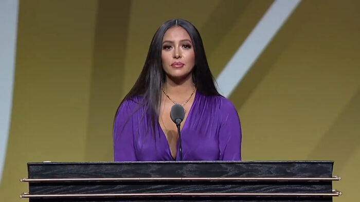 Woman in purple dress speaking at event podium