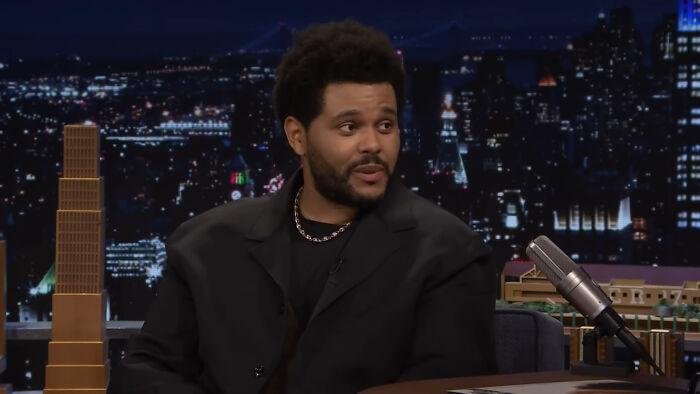 Man in black jacket talking on late night show about celebrity encounters
