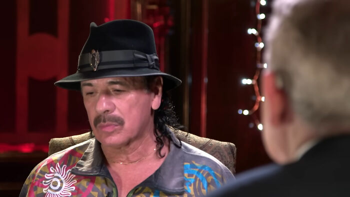 Man in colorful shirt and black hat in celebrity interview setting