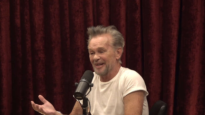 Man in white tee discussing disappointing celebrity encounters on podcast
