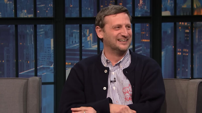 Laughing celebrity wearing a jacket on a talk show about disappointing celebrity encounters