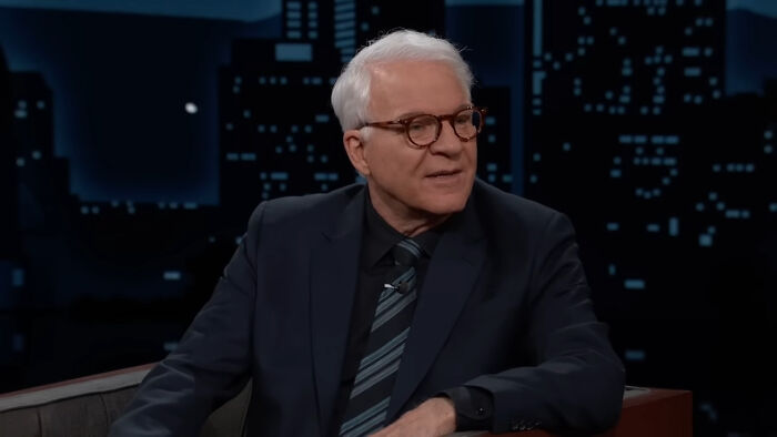 Man in suit and glasses on late night celebrity talk show