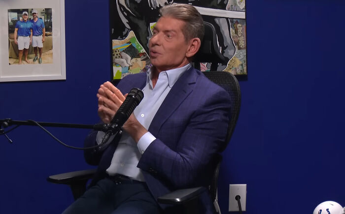 Man in suit talks about disappointing celebrity encounters during podcast