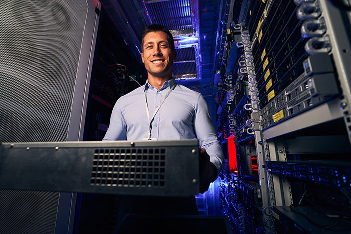 Smiling IT worker in server room showing fired employees tech jobs