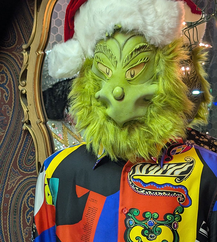 Green Grinch character in Santa hat symbolizing fired employees