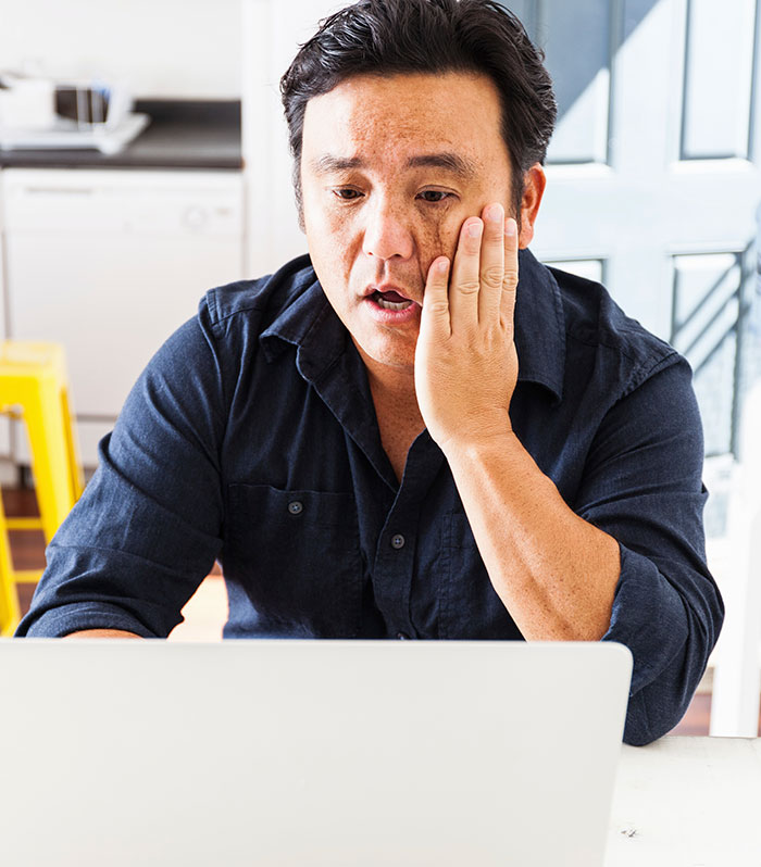 Shocked man working on laptop after getting fired for ridiculous reasons