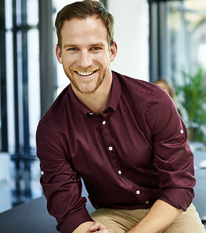 Smiling man in burgundy shirt representing employees fired for ridiculous reasons