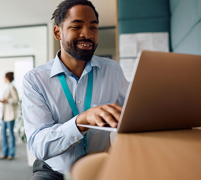 Smiling employee working on laptop in office showing fired employees