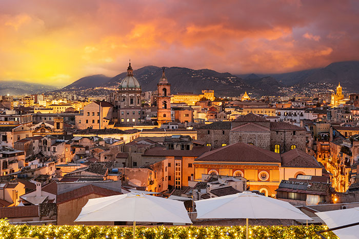 Cityscape at sunset with historic buildings and mountain backdrop