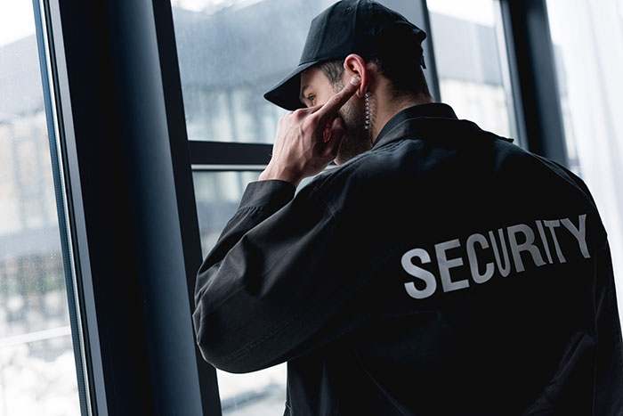 Security guard using earpiece and looking out window