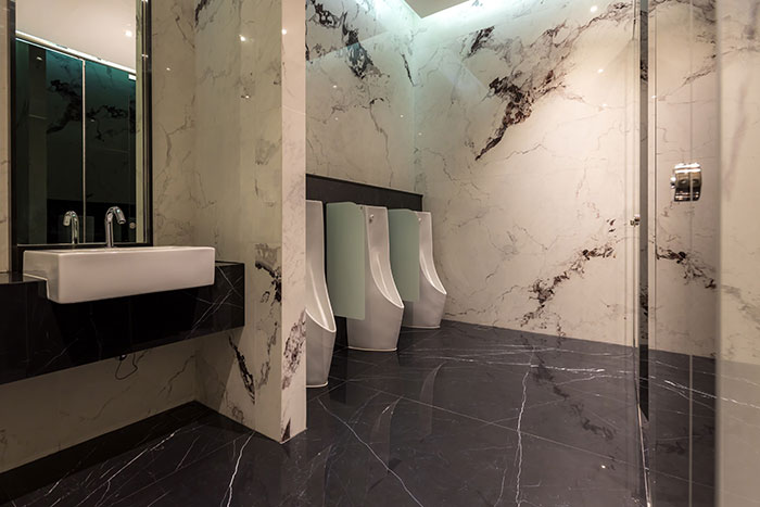 Modern public restroom with urinals and marble walls and floors