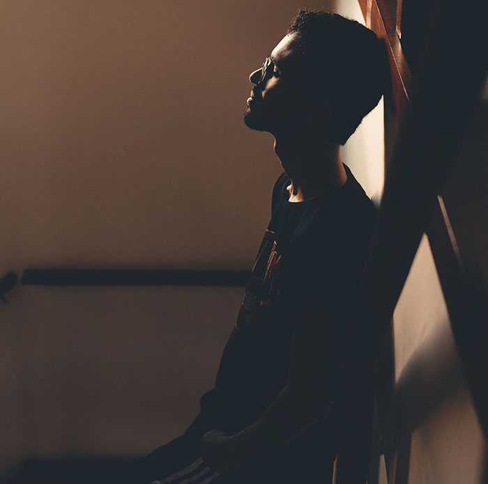 Man sitting alone in shadow reflecting on friendship realization