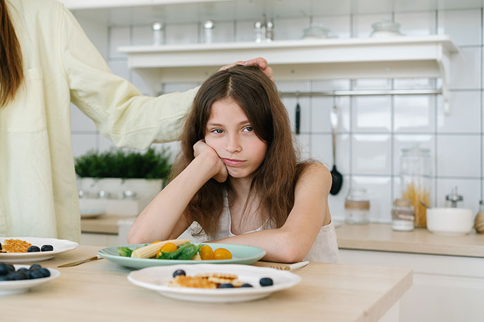 Bored girl ignored at kitchen table depicting fake friend feelings